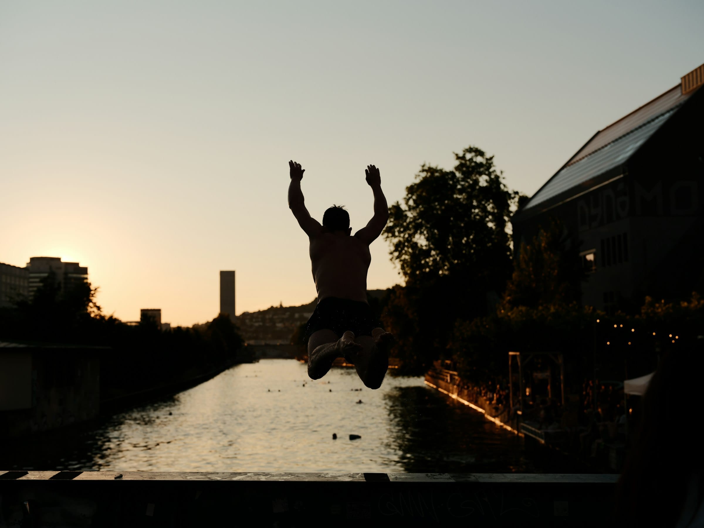 Someone jumping into the Limmat at sunset, arms raised